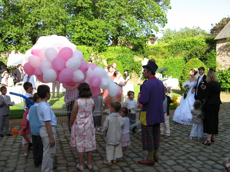 Les mari&eacute;s regardent le clown et les enfants qui pr&eacute;parent le l&acirc;cher de ballons